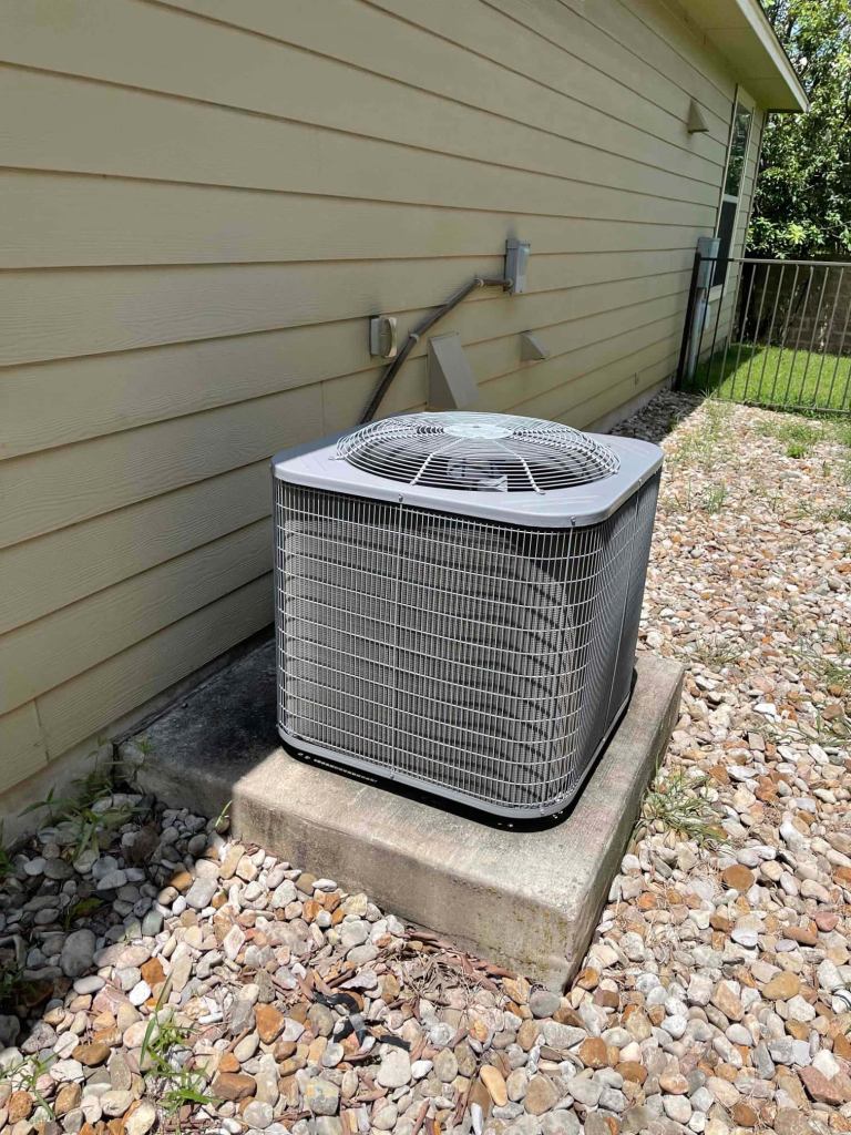 outdoor AC unit installed on concrete pad surrounded by gravel